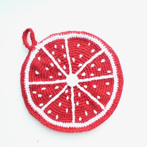 Pode incluir: Um pegador de panela de crochê vermelho e branco em forma de fatia de fruta cítrica. O pegador de panela tem uma alça de laço.