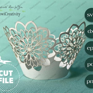 May include: A white cupcake wrapper with a delicate floral design. The wrapper is made of paper and has a cut-out pattern. The wrapper is on a turquoise surface. The text "CUT FILE" is visible in the lower left corner of the image. The text "DowiCreativity" is visible in the upper left corner of the image. The text "svg", "dxf", "eps", "pdf", and "png" are visible in the upper right corner of the image.