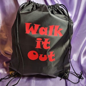 May include: Black drawstring bag with red text that says "Walk it Out".