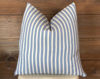 May include: A white and blue striped pillow with a blue and white striped pattern. The pillow is sitting on a white stool with a metal frame.