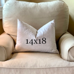 May include: A white pillow with the text "14x18" printed on it, sitting on a beige armchair.