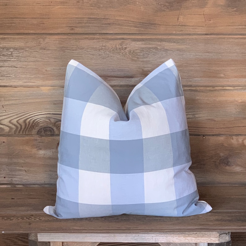 May include: A blue and white gingham pillow with a soft, textured fabric. The pillow is sitting on a wooden surface.