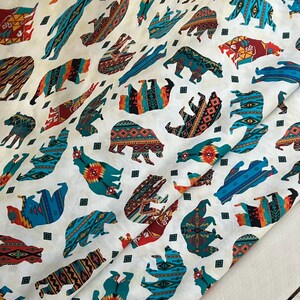 May include: White fabric with a repeating pattern of bears in various poses. The bears are decorated with colorful geometric patterns in shades of teal, orange, red, and brown. Small black squares are scattered throughout the design.