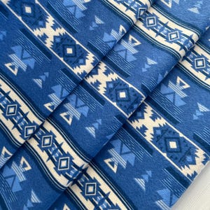 May include: Blue and white patterned fleece fabric with a geometric design. The fabric is soft and comfortable, perfect for crafting projects.