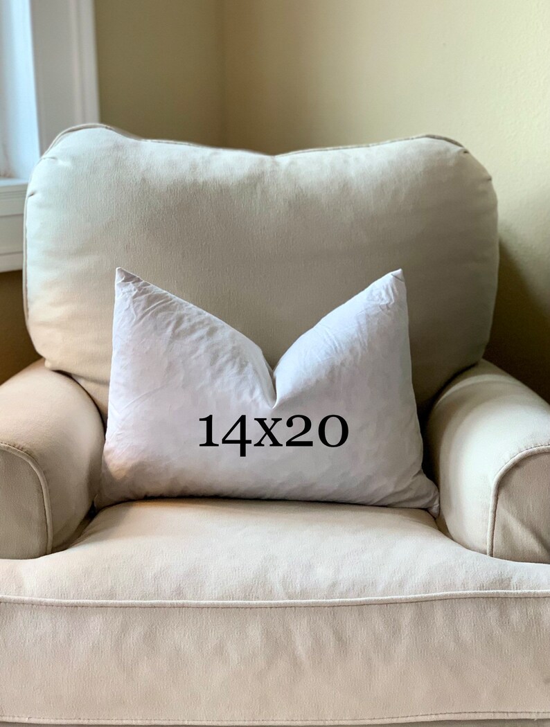 May include: A white pillow with the text "14x20" printed on it, sitting on a beige armchair.
