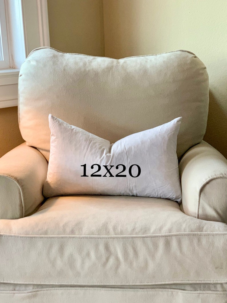 May include: A white pillow with the text "12x20" printed on it. The pillow is sitting on a beige armchair.