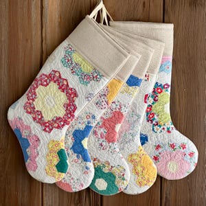 Puede incluir: Cinco calcetines de Navidad de estilo vintage hechos de tela acolchada con un patrón floral en tonos de rosa, amarillo, azul, verde y rojo. Los calcetines están forrados con una tela de lino natural.