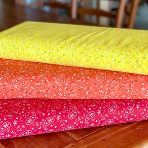 May include: Three fabric swatches with a paisley pattern. The top swatch is yellow with white paisley, the middle swatch is orange with white paisley, and the bottom swatch is red with white paisley.