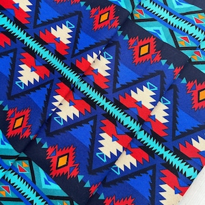 Puede incluir: Tela con estampado geométrico azul, rojo, blanco y naranja con un diseño del suroeste.