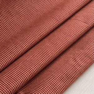 Könnte beinhalten: Rot-weiß gestreiftes Gewebe mit einer dezenten Textur. Der Stoff ist gefaltet und drapiert, wodurch das Muster und die Webart sichtbar werden.