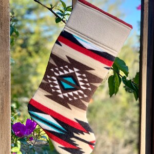 May include: A beige, red, brown, black, and turquoise Christmas stocking with a geometric pattern.