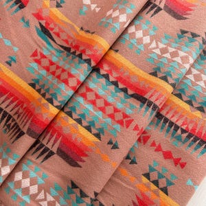 Op de afbeelding: Een close-up van een stof met een geometrisch patroon in tinten rood, oranje, geel, blauw en groen. De stof heeft een zachte, textuur en is perfect voor knutselprojecten.