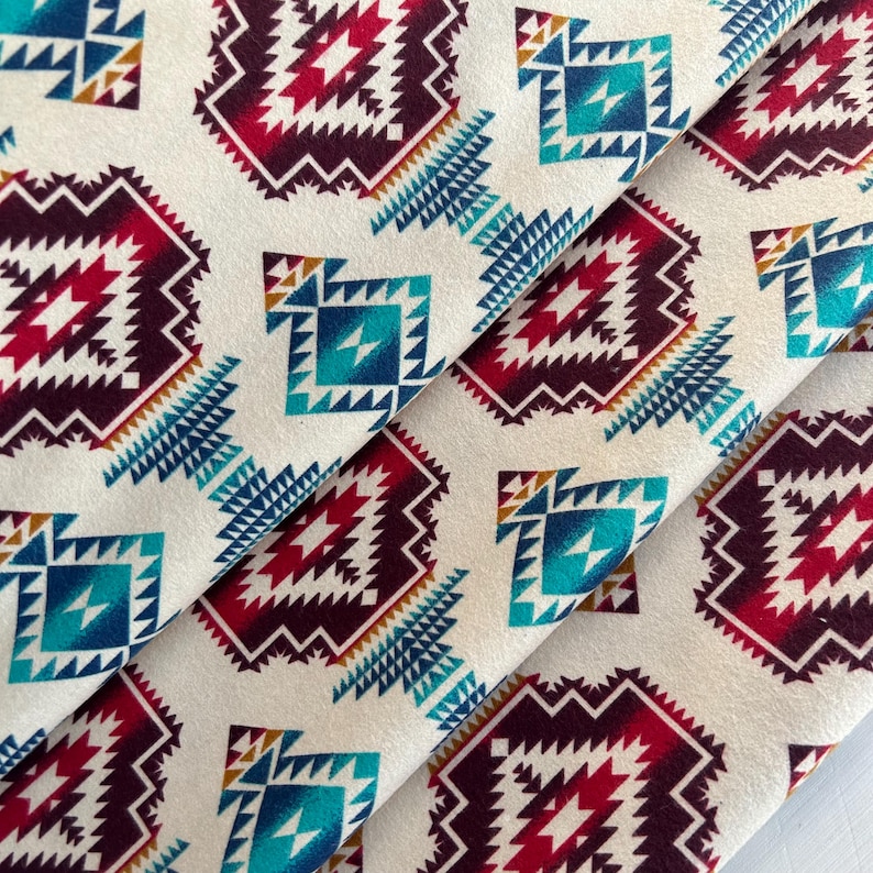 May include: A white fabric with a repeating geometric pattern in shades of red, blue, teal, and brown. The pattern is reminiscent of Native American designs.