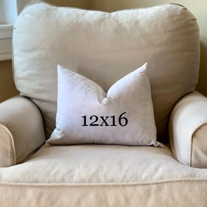 May include: A white pillow with the text "12x16" printed on it, sitting on a beige armchair.