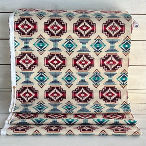May include: Beige fabric with a repeating geometric pattern in shades of red, blue, and brown. The pattern features a large diamond shape with smaller diamond shapes inside. The fabric is folded in thirds.