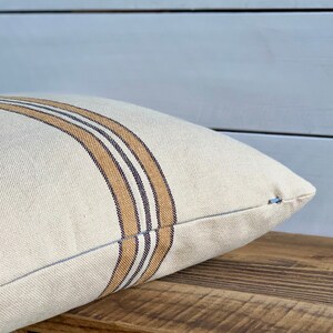 May include: A white pillow with brown and black stripes. The pillow is made of a soft, textured fabric.
