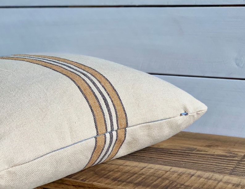 May include: A white pillow with brown and black stripes. The pillow is made of a soft, textured fabric.