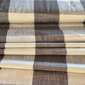 May include: Brown and white checkered fabric with a textured weave. The fabric is folded in thirds, showing the pattern.