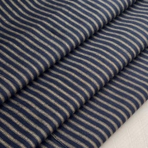 Könnte beinhalten: Nahaufnahme eines blau-weiß gestreiften Stoffes. Der Stoff ist dreifach gefaltet, wobei die Streifen horizontal verlaufen.