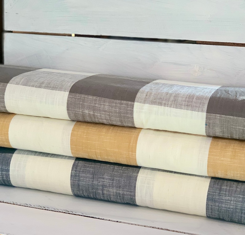 May include: Three fabric swatches in a stack. The top swatch is a white and gray gingham pattern. The middle swatch is a white and tan gingham pattern. The bottom swatch is a white and dark gray gingham pattern.