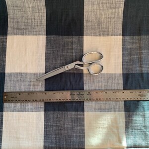 May include: A white and black checkered fabric with a pair of silver scissors and a ruler measuring 18 inches.