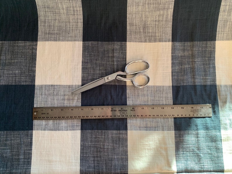 May include: A white and black checkered fabric with a pair of silver scissors and a ruler measuring 18 inches.