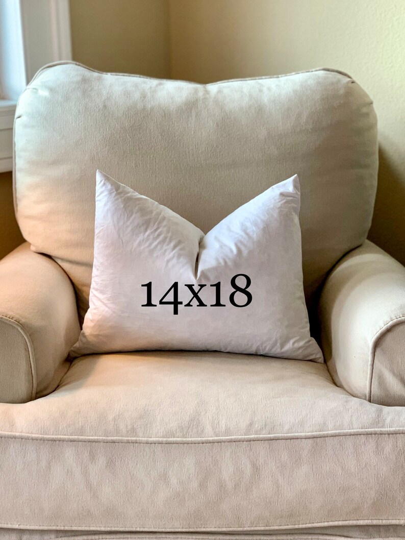 May include: A white pillow with the text "14x18" printed on it, sitting on a beige armchair.