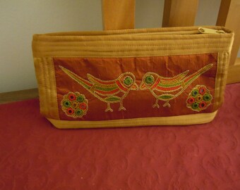 An embroidered, multi-purpose clutch / pouch / bag made in silk fabric from Gujarat province in India. Use it for cosmetics or for toiletry.
