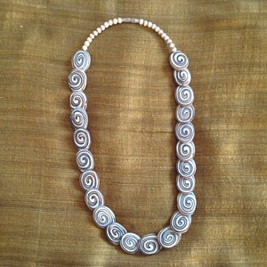 May include: A white and brown spiral patterned necklace with a silver clasp.