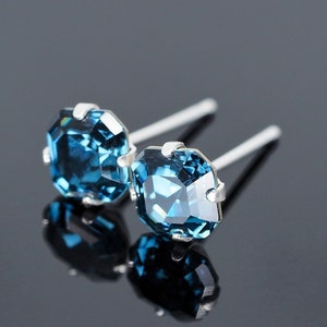 May include: A pair of silver stud earrings with dark blue square-shaped gemstones.