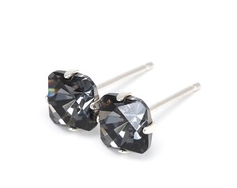 Puede incluir: Un par de pendientes de plata con piedras cuadradas negras.