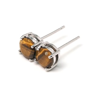 Op de afbeelding: Een paar zilveren oorbelletjes met ronde tijgeroogstenen.