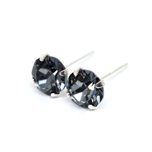 May include: A pair of silver stud earrings with dark grey round crystal stones.