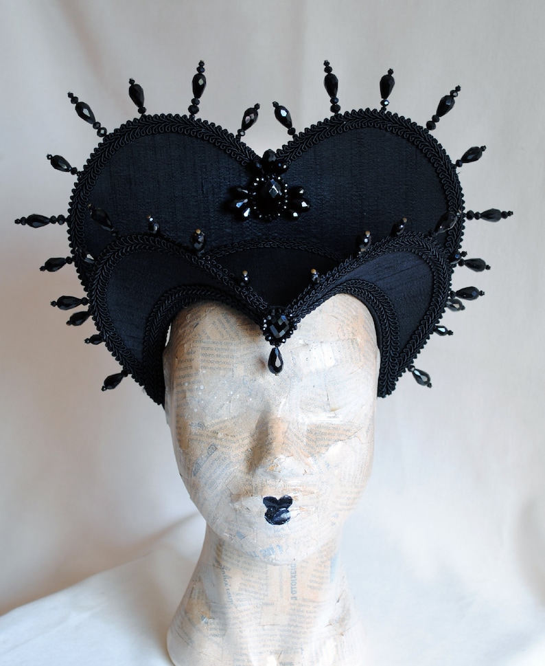 May include: A black heart-shaped headpiece with black bead embellishments and a black jewel in the center.