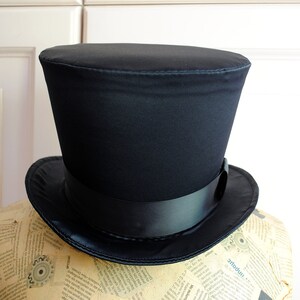 May include: A black top hat with a wide brim and a black satin ribbon.