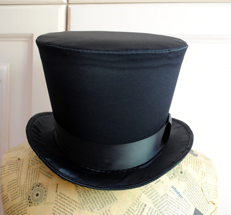 May include: A black top hat with a wide brim and a black satin ribbon.