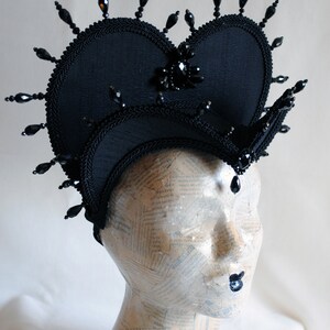 May include: A black fabric crown with a heart-shaped top and black bead embellishments.