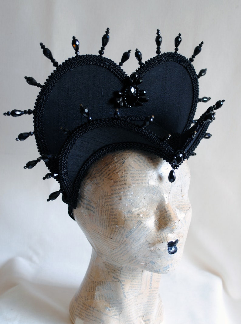 May include: A black fabric crown with a heart-shaped top and black bead embellishments.