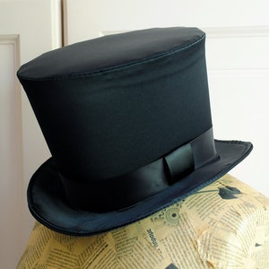 May include: A black top hat with a wide brim and a black satin ribbon.