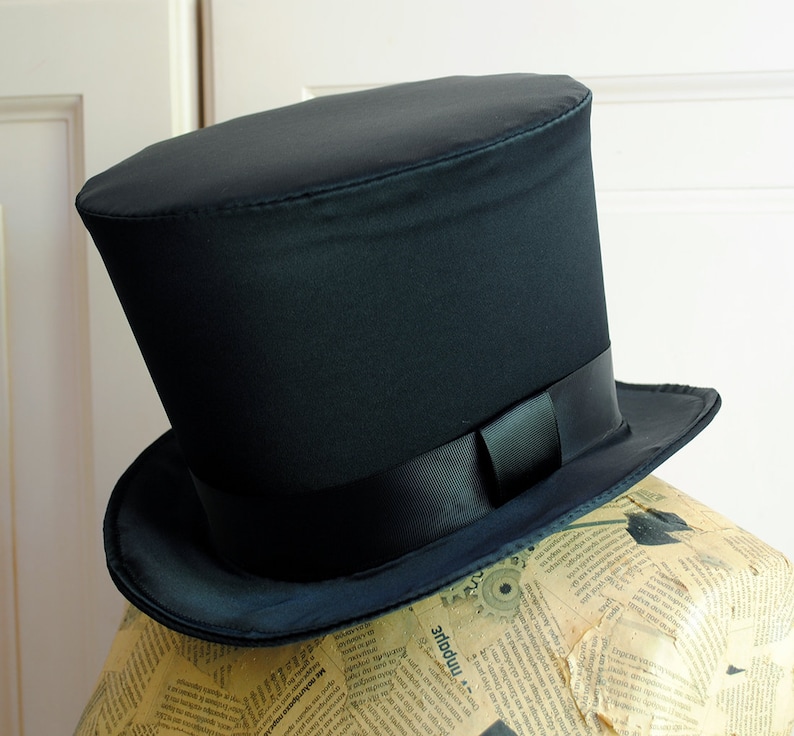 May include: A black top hat with a wide brim and a black satin ribbon.
