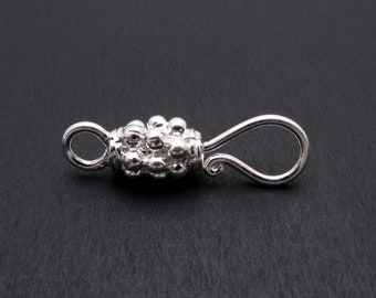 May include: Silver-toned clasp with a textured, beaded design. The clasp has a loop on one end and a hook on the other.