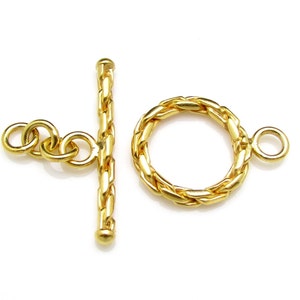 May include: Gold-toned metal toggle clasp with a braided rope design. The clasp has a round ring and a bar with two connecting rings.