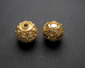 May include: Two gold-toned round beads with a textured surface and a circular design. The beads have a hole in the center for stringing.