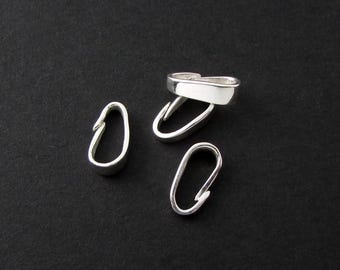 以下が含まれることがあります： 黒い背景に配置された、銀色のジュエリークラスプのコレクション。 クラスプは楕円形で、フック留めが付いています。 画像は、デザインと仕上げを強調するために、さまざまな角度からクラスプを表示しています。