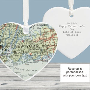 May include: A white ceramic heart-shaped ornament with a vintage map of New York City on one side. The other side is blank and has the text "To Liam Happy Valentine's Day Lots of love Amelia x".