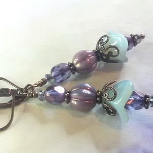 Purple fire polished faceted Czech glass beads accent milky lavender melon beads and flower shaped aquamarine and teal colored focal beads