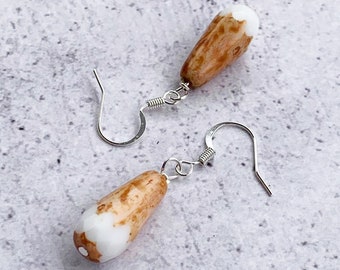 May include: A pair of dangle earrings with brown and white teardrop-shaped beads and silver hooks.