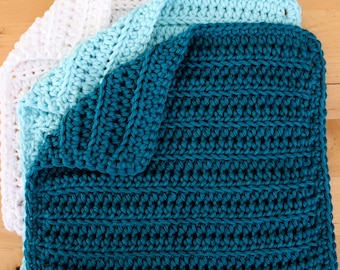 Puede incluir: Tres paños de cocina de ganchillo apilados uno encima del otro. El paño de cocina superior es de color turquesa, el del medio es azul claro y el inferior es blanco.