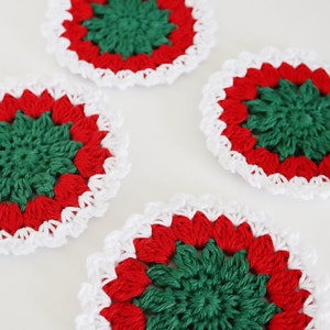 May include: Four crocheted coasters in red, green and white. The coasters have a scalloped edge and a centre design with a starburst pattern.