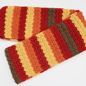 May include: A crocheted scarf with a striped pattern in shades of brown, red, orange, and yellow.